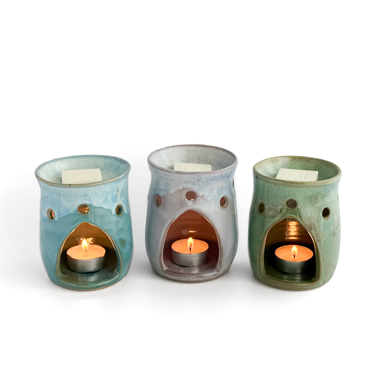 A trio of Leonore wax melt warmers in Hazel Green, Lavender Haze and Azure Blue, with Rosie & B wax melts and glowing tealights