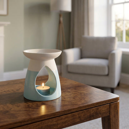 Arabella ceramic wax warmer in powder blue, with a glowing tea light, in a living room setting